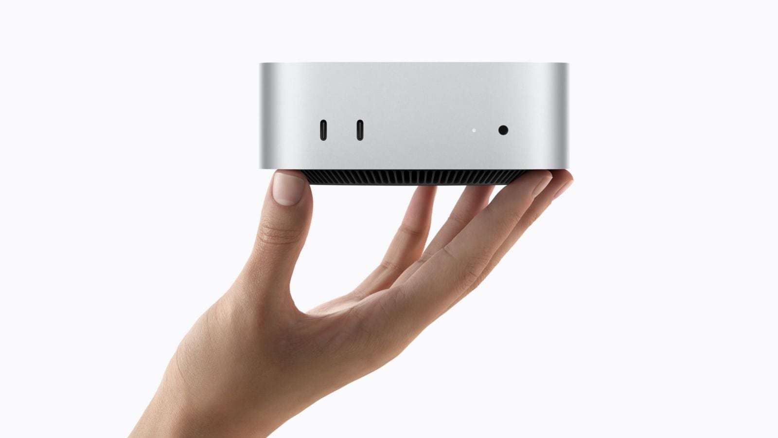 Ruka drží stříbrný Mac mini se zobrazenými předními porty