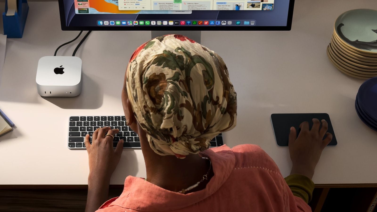 Pohled shora na osobu u klávesnice a myši, Mac mini připojený k velkému displeji