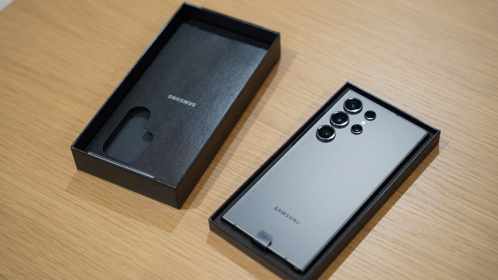 Rozbalený Samsung Galaxy S23 Ultra, viditelný zadní fotoaparát, stříbrno-titanová barva, víko krabice vedle